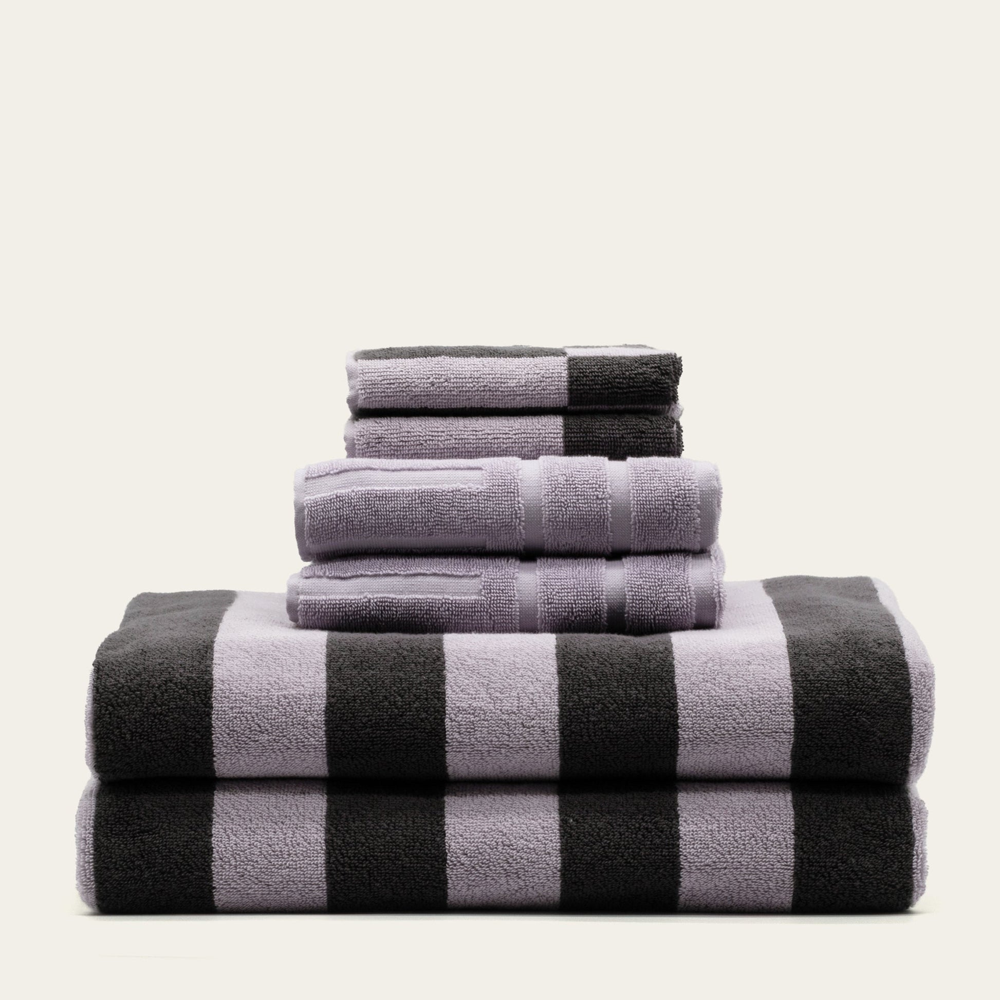 Stack of cotton towels in lilac and charcoal, black-and-lilac checker stripe pattern