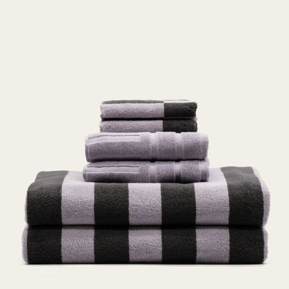 Stack of cotton towels in lilac and charcoal, black-and-lilac checker stripe pattern