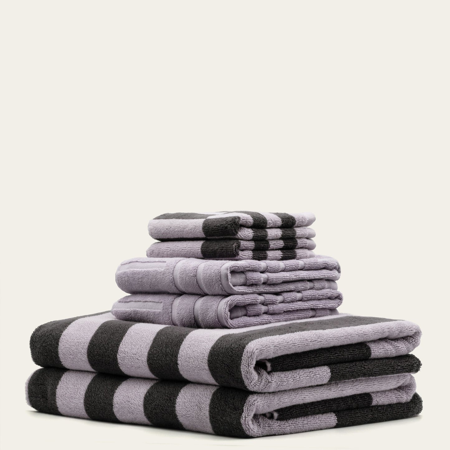 Folded cotton towels in lilac and charcoal with black-and-lilac wide stripe pattern