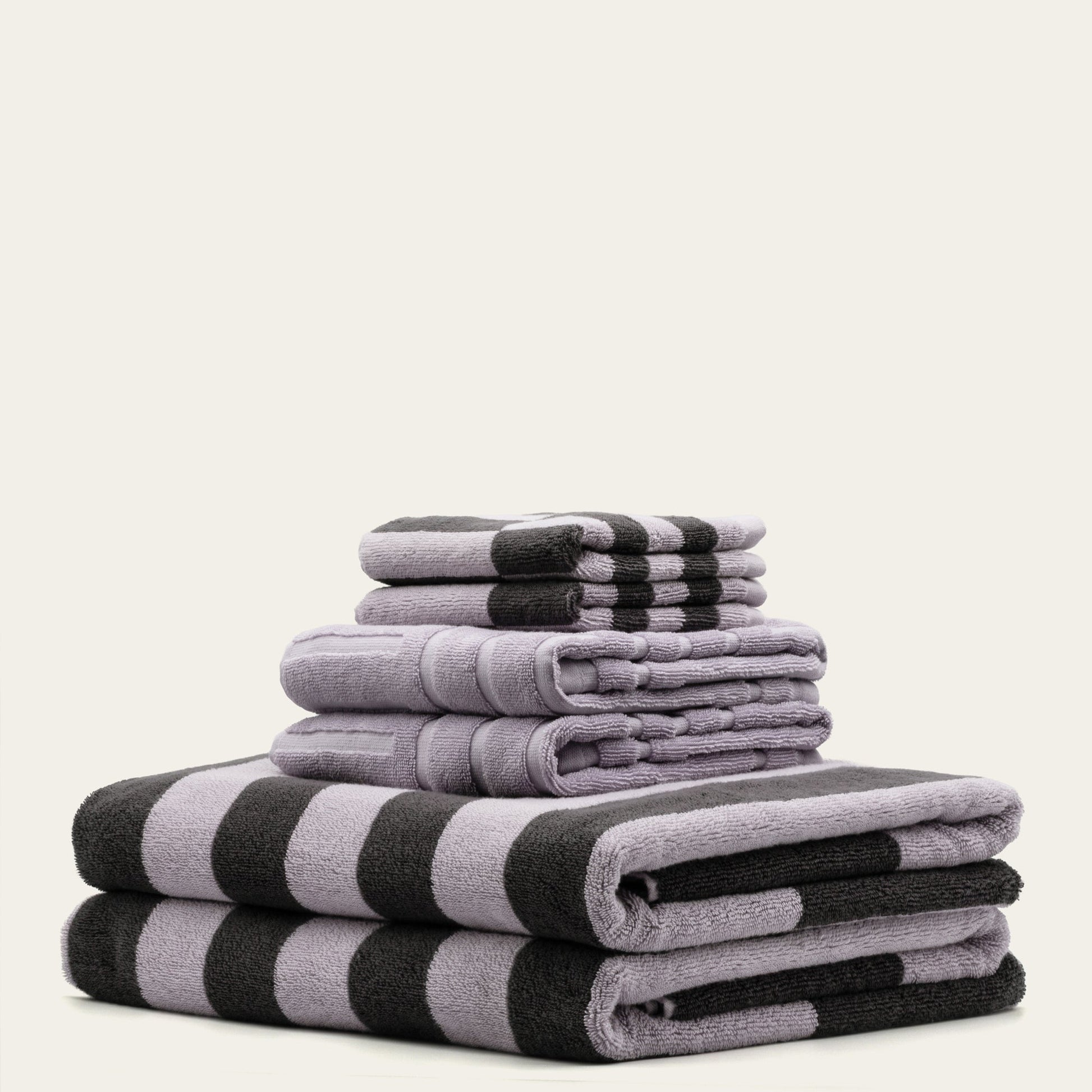 Folded cotton towels in lilac and charcoal with black-and-lilac wide stripe pattern
