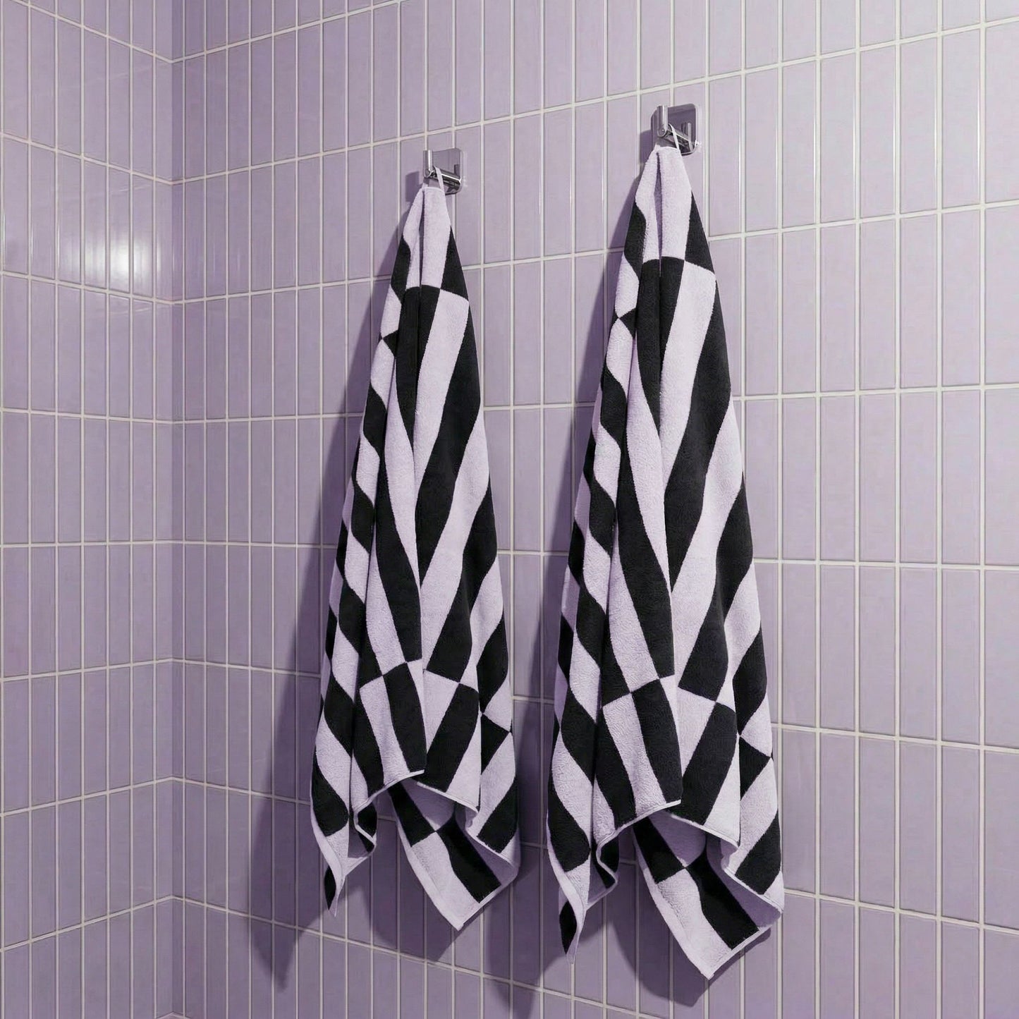 Hanging cotton towels in lilac and charcoal with bold black-and-lilac checker stripes