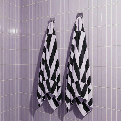 Hanging cotton towels in lilac and charcoal with bold black-and-lilac checker stripes