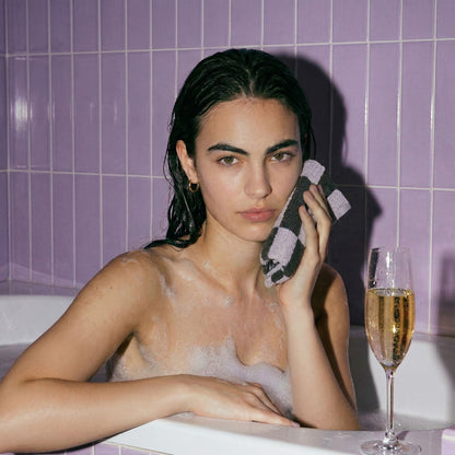 Lilac and charcoal checkered washcloth held to the face