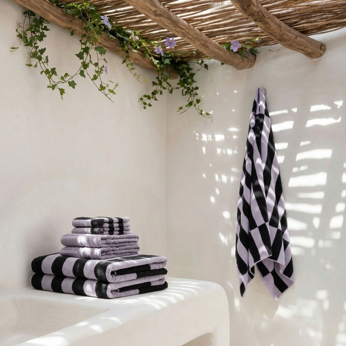 Cotton towels stack with lilac and black-and-white striped towels, plus hanging towel