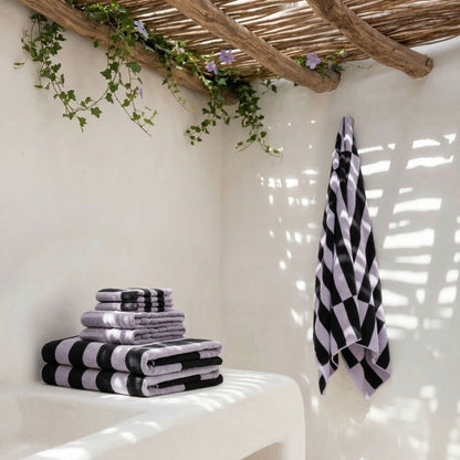 Cotton towels stack with lilac and black-and-white striped towels, plus hanging towel
