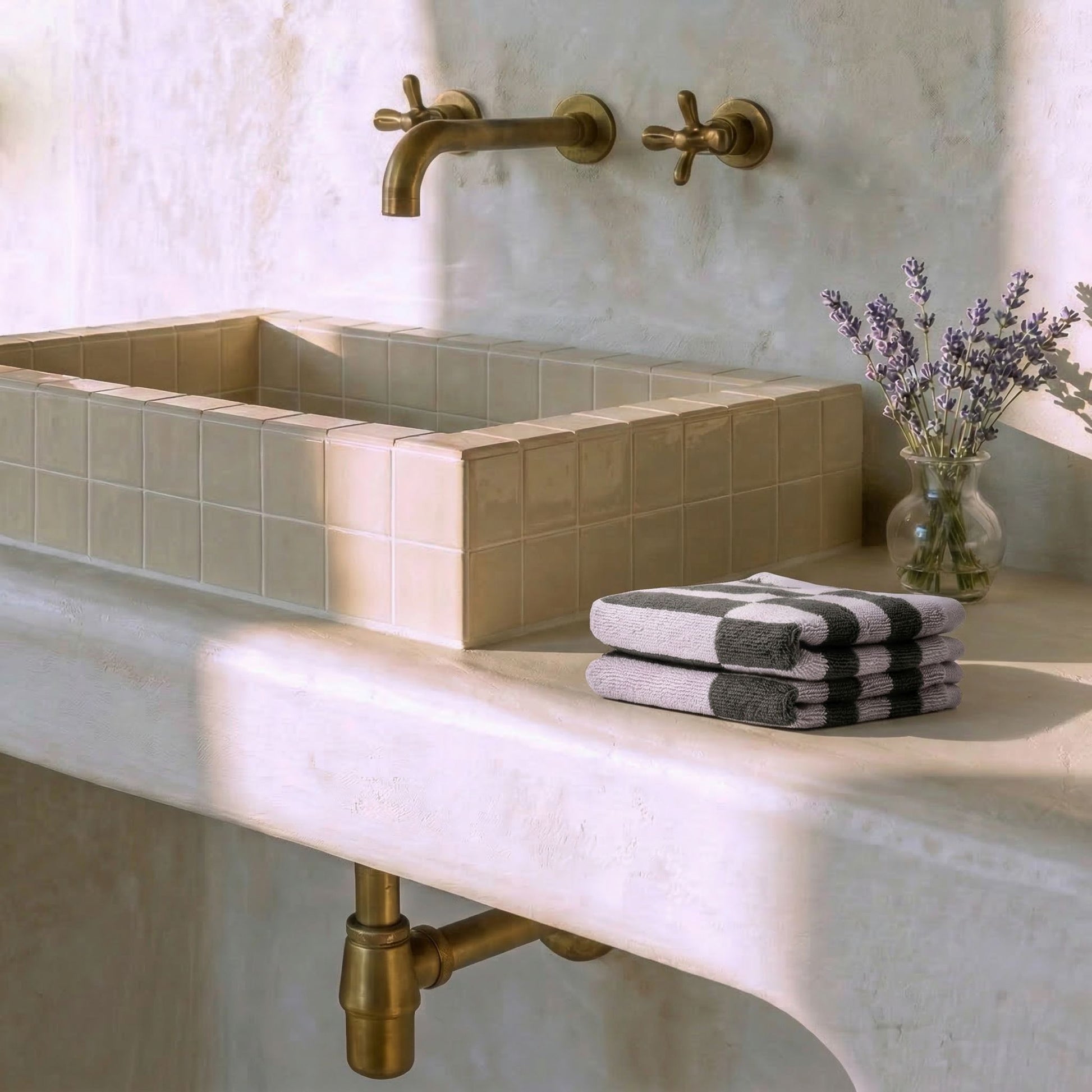 Lilac and charcoal checkered cotton towels stacked on a bathroom sink