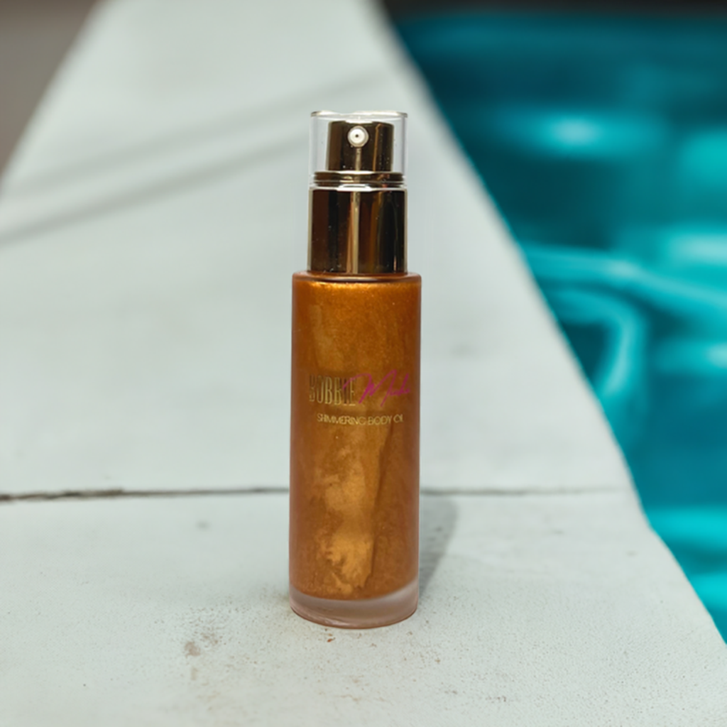 Shimmering body oil bottle with gold spray cap and amber-gold shimmer finish