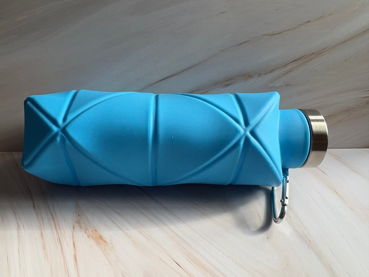 Blue silicone collapsible water bottle with stainless cap, carabiner clip, and textured sides