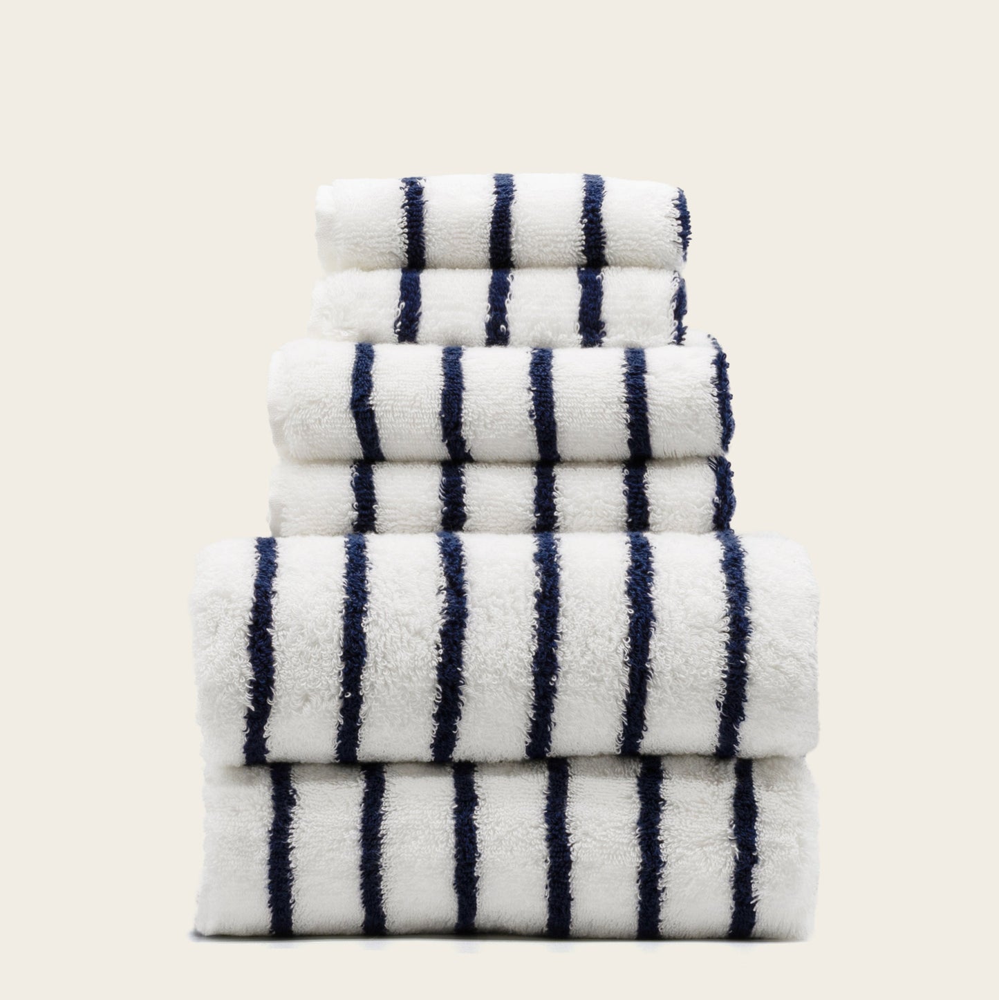 Stacked plush cotton towels, white with navy vertical stripe pattern, folded.