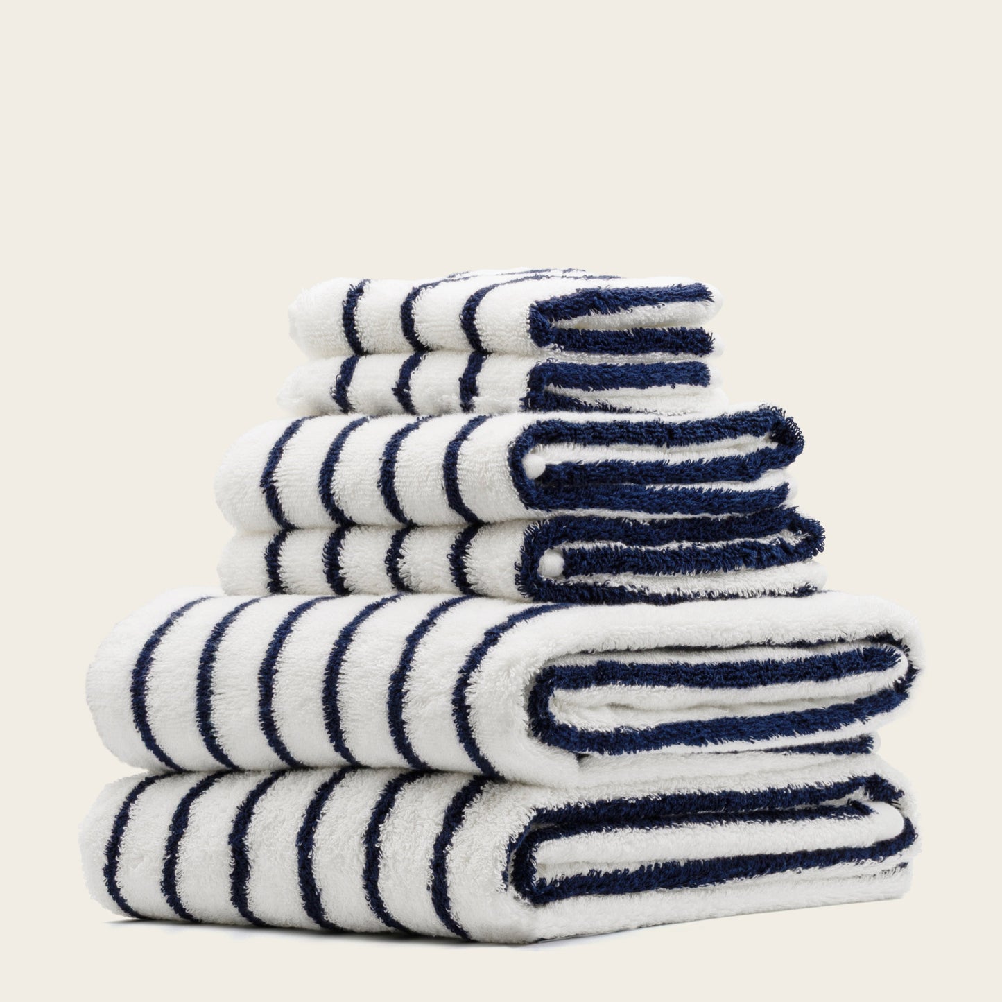 White towels with navy blue stripes, folded pile with plush terry weave.