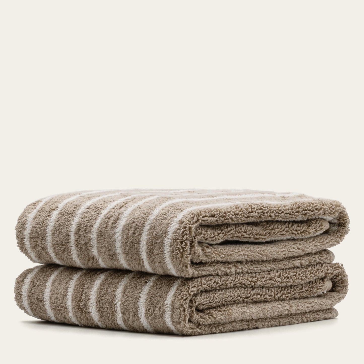 Striped cotton bath towels, folded stack showing terry texture and taupe-white stripes