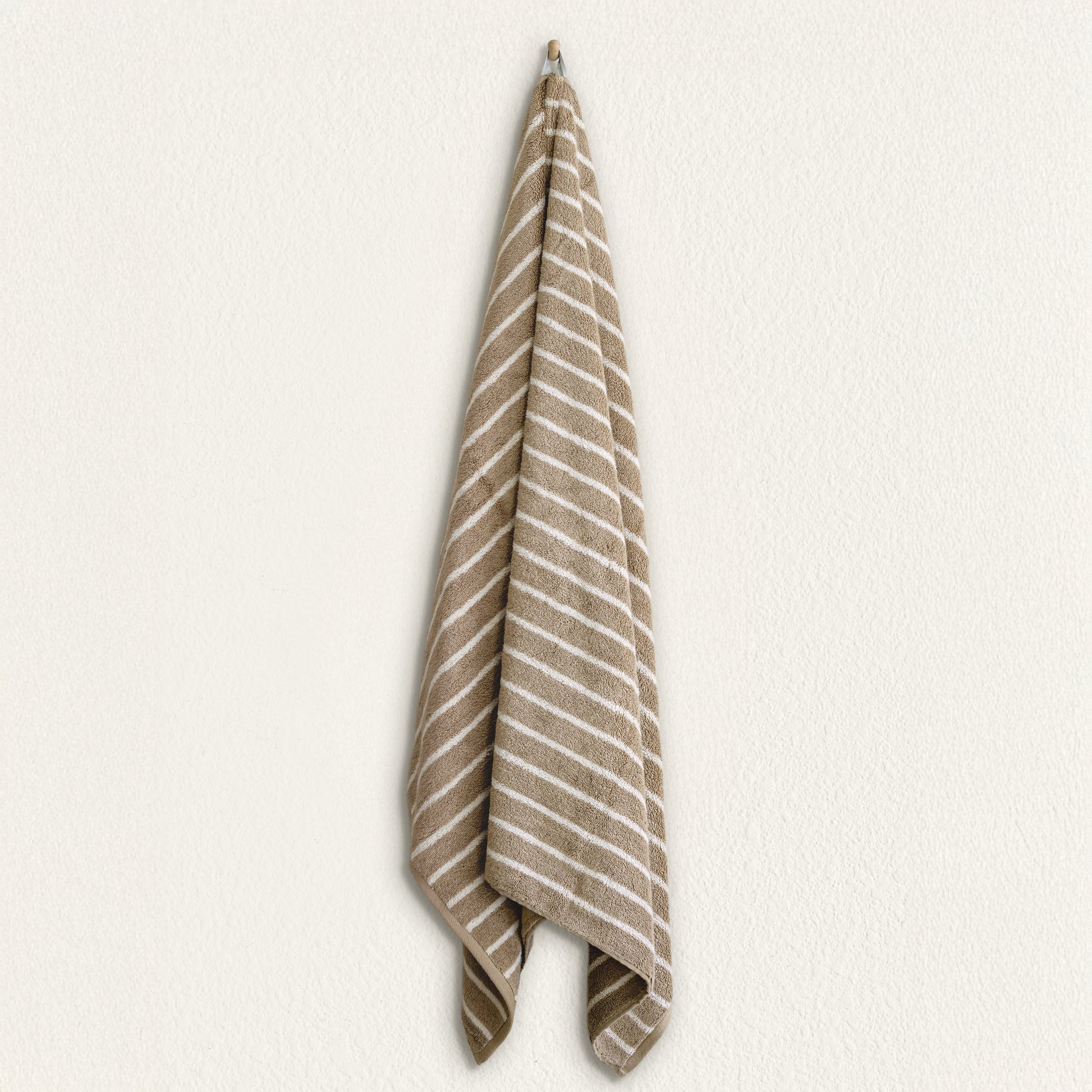 Striped cotton hand towel hanging, taupe and white stripe pattern on terry fabric