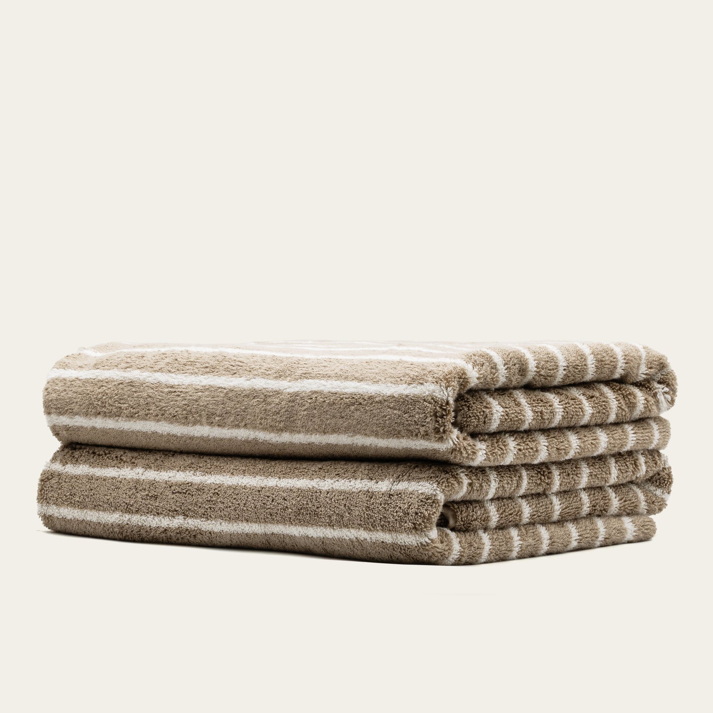 Striped cotton towels, neatly folded with taupe and white stripes, visible terry loops
