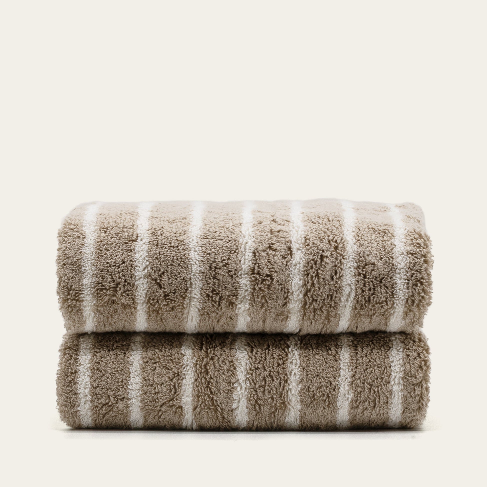 Striped cotton bath towels, folded stack with taupe base and white vertical stripes