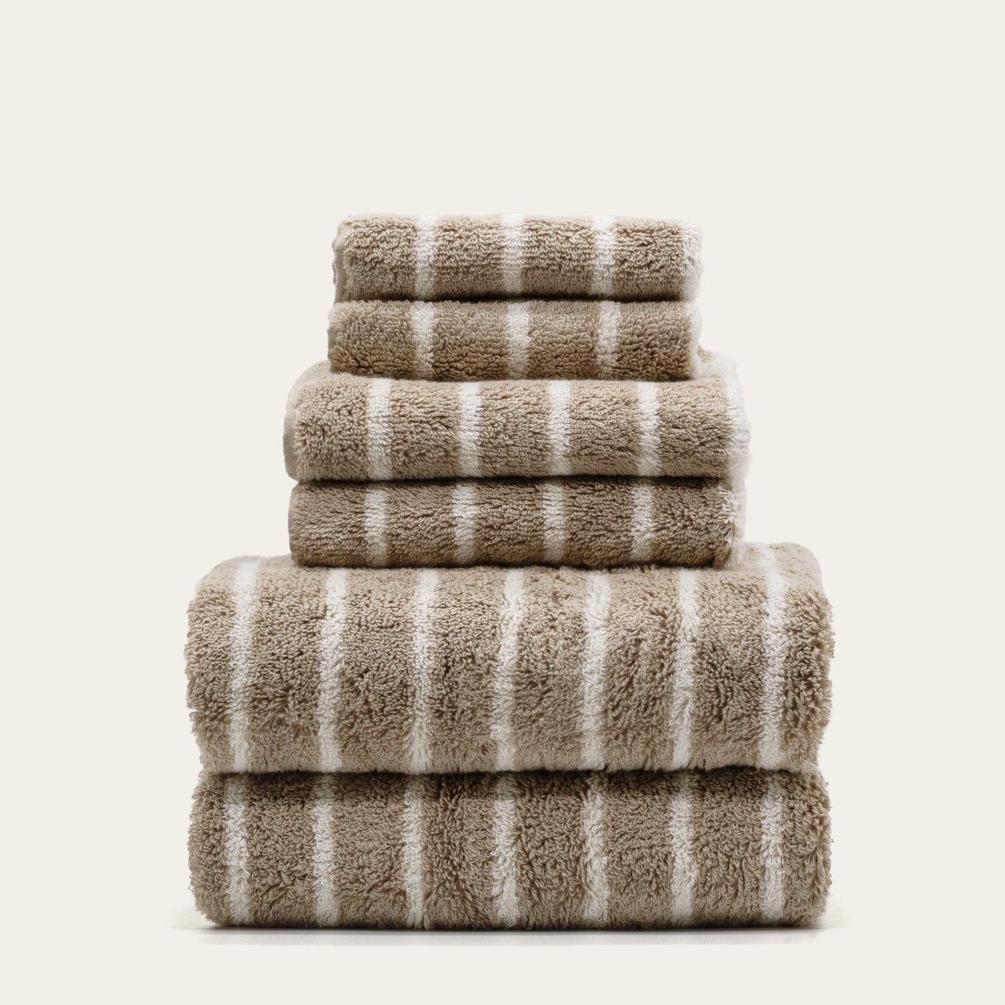 Striped cotton towel stack, folded into tiers with taupe fabric and white stripes