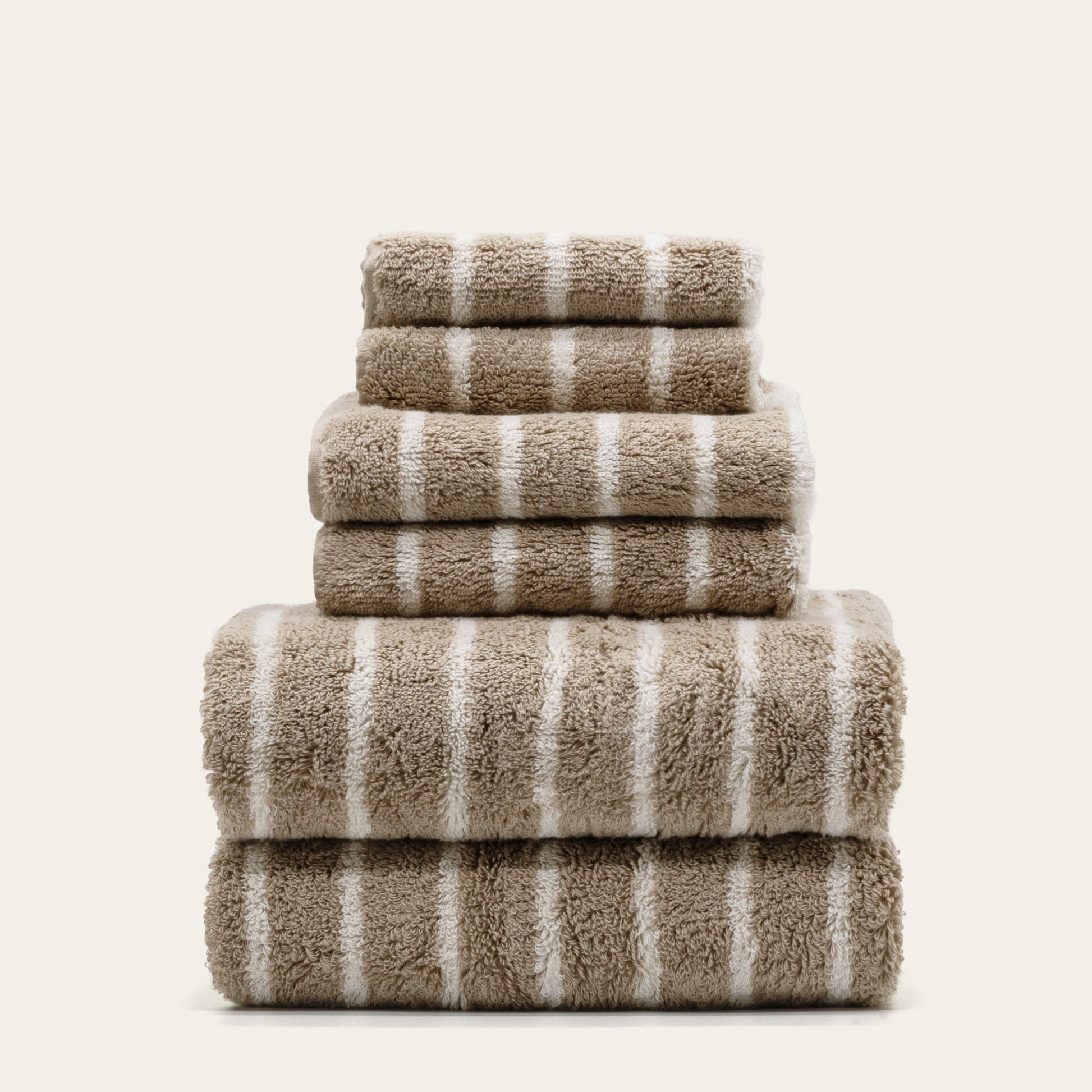 Striped cotton towel stack, folded into tiers with taupe fabric and white stripes