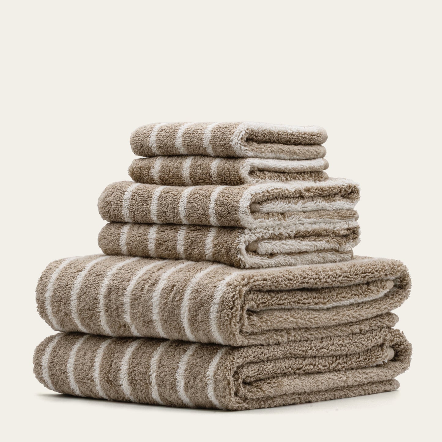 Striped bath towels stack, beige and white plush cotton loops