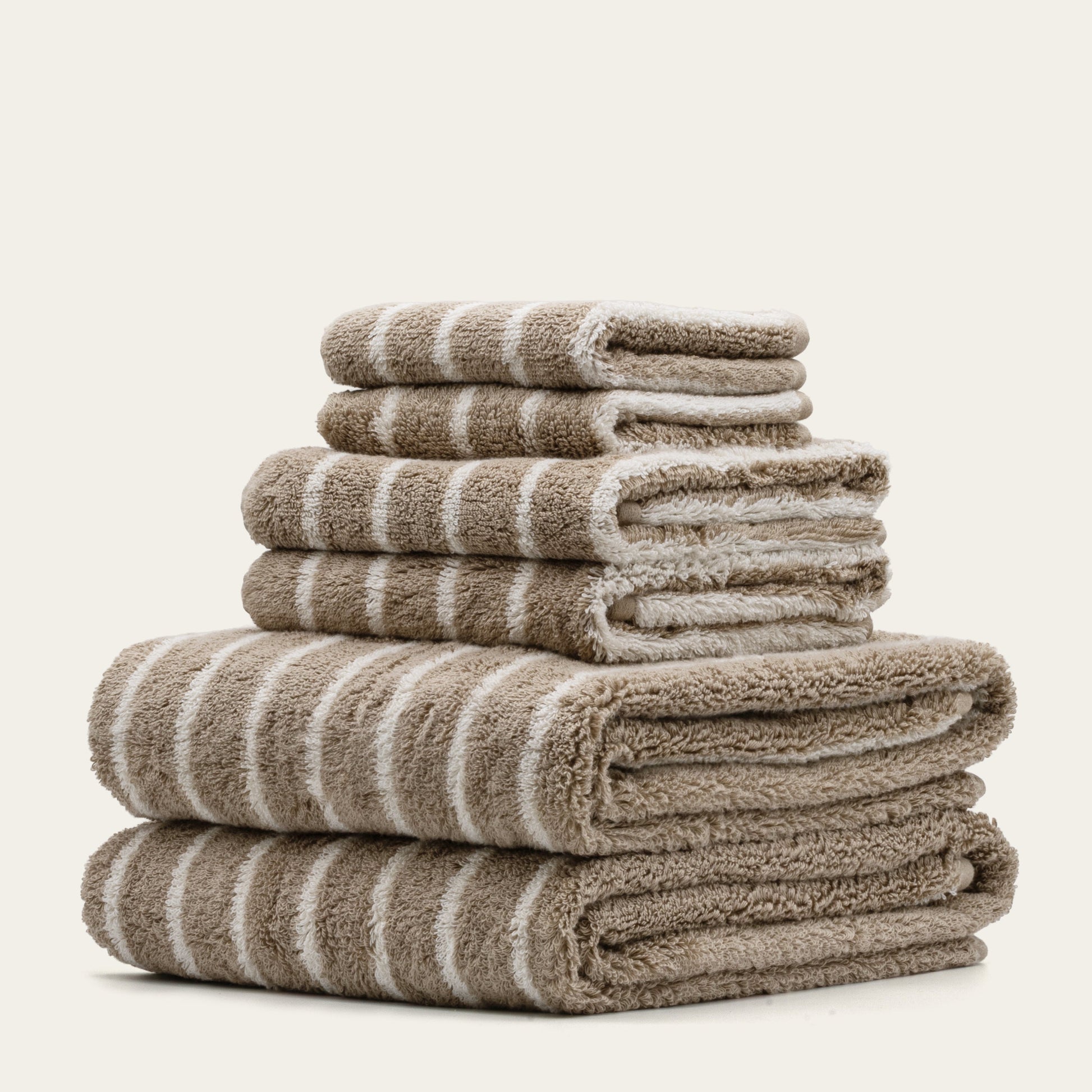 Striped bath towels stack, beige and white plush cotton loops