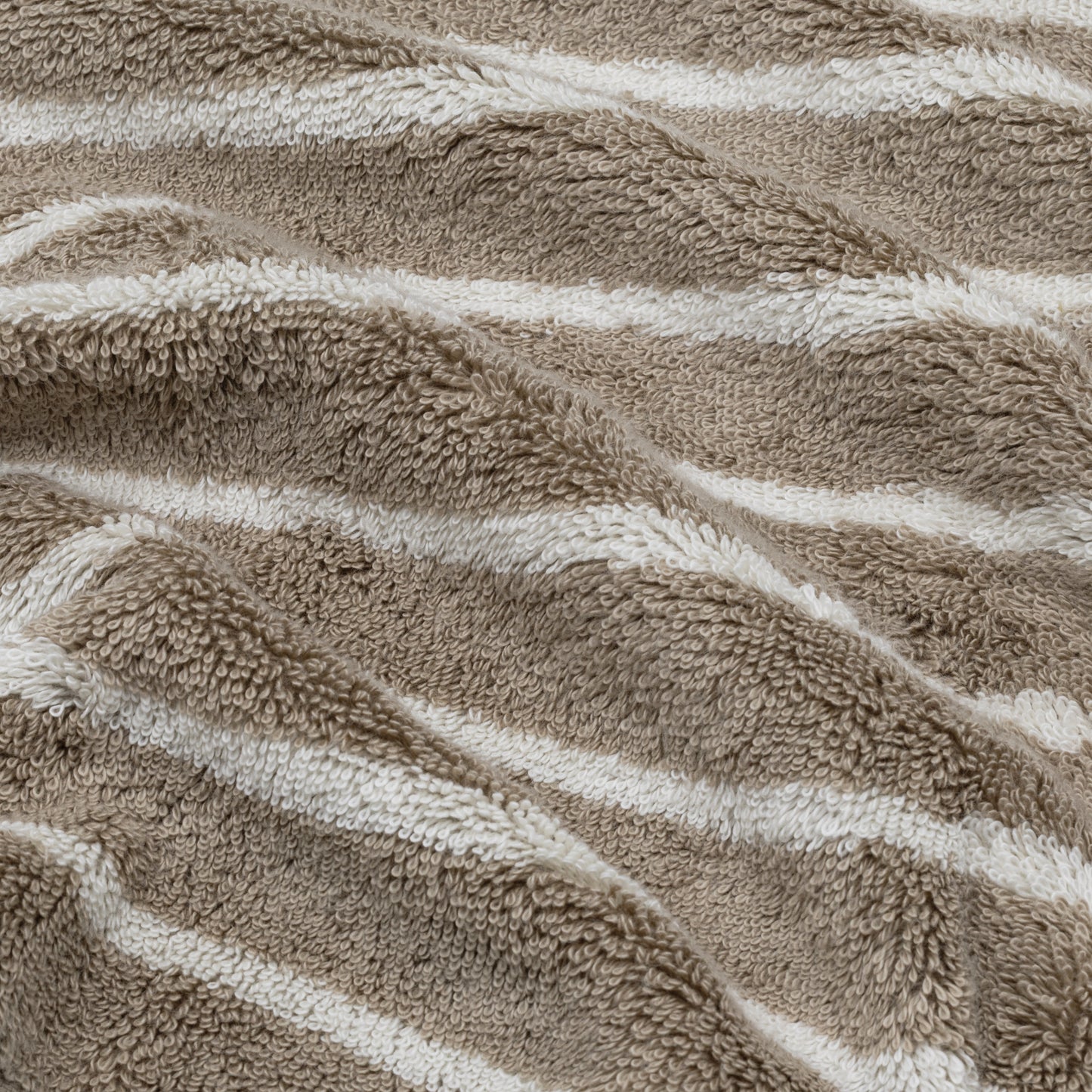 Striped terry cotton towel close-up, with beige and white bands