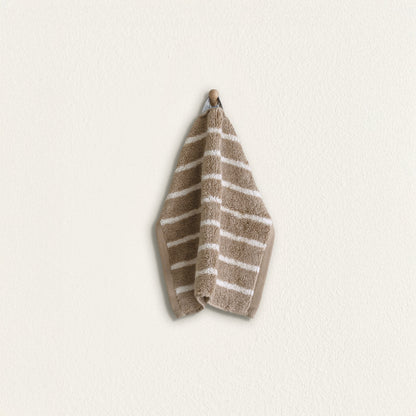 Striped cotton hand towel hanging, taupe with white stripes and folded terry texture
