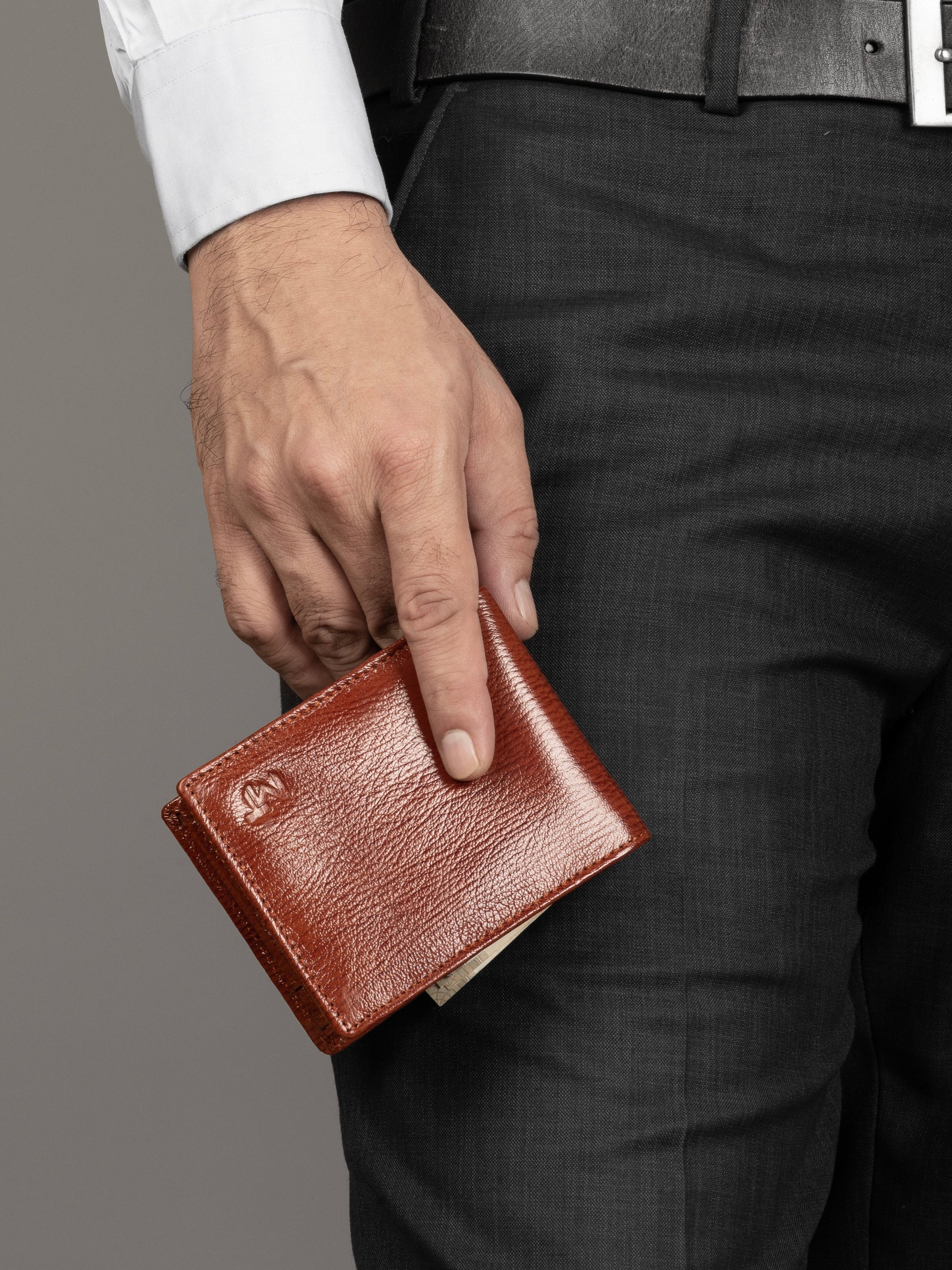 Men's tan-brown leather wallet held in hand, front cover facing up