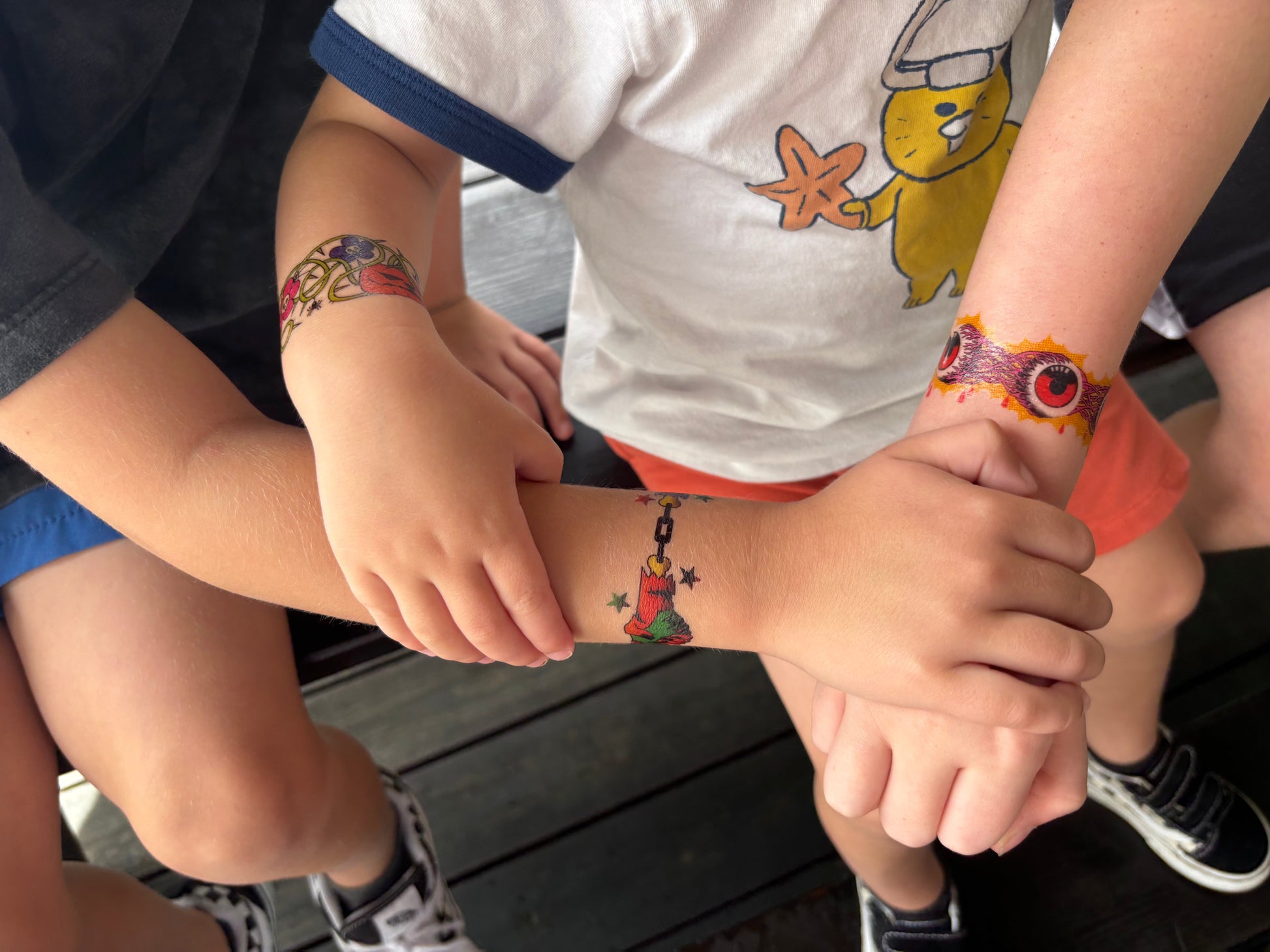 Temporary kids tattoo band on child’s arms, colorful Halloween icons near hands
