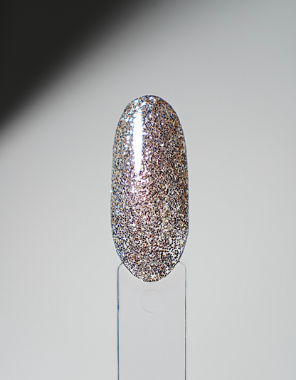 Glossy nail polish swatch tip in dense gold-and-silver glitter on a clear display holder.