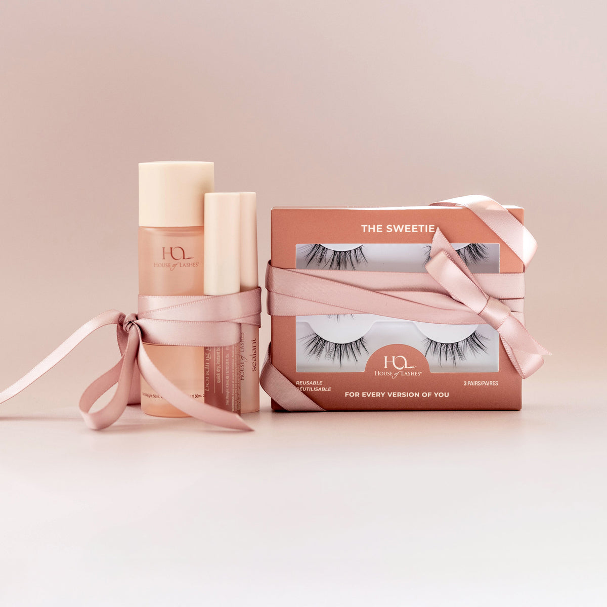 Lash routine set with pink gift boxes and bottles, tied ribbon packaging