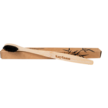 Bamboo toothbrush in cardboard box with black bristles and bamboo handle