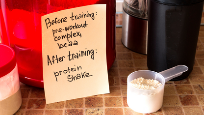 BCAA powder scoop with handwritten training note beside shaker bottles