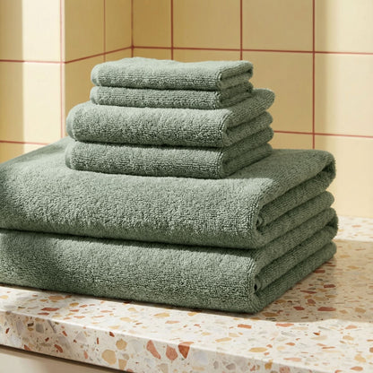 Stack of green plush towels, neatly folded with thick terry loops