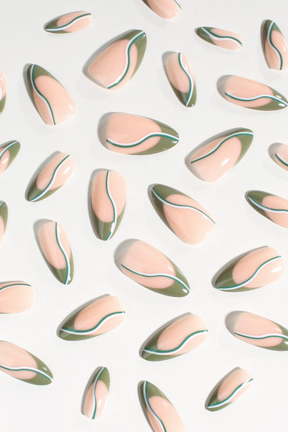 Oval press-on nails laid out, nude base with green edges and thin black swoop lines