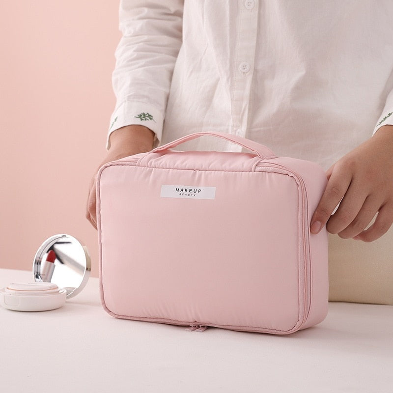 Pink cosmetic bag with top handle, front zipper panel, and side pocket