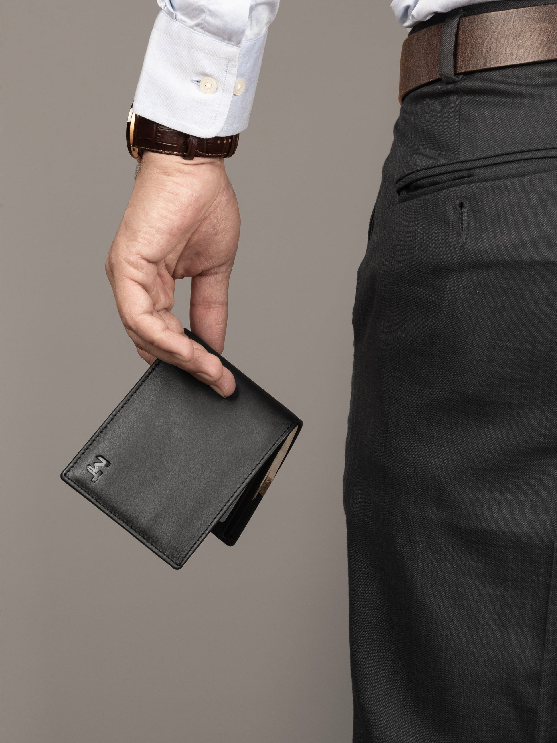 Black bi-fold wallet held by a person, front panel visible with MT logo