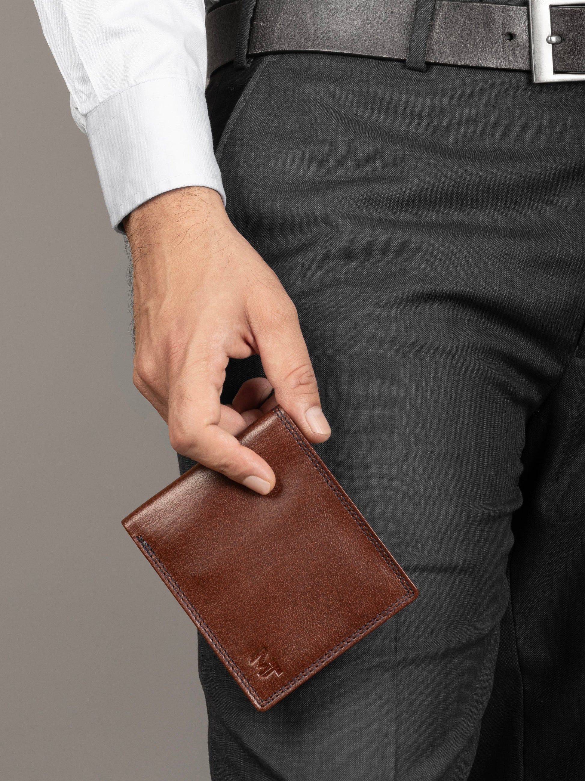 Brown leather cash and card holder held in hand, embossed logo on front