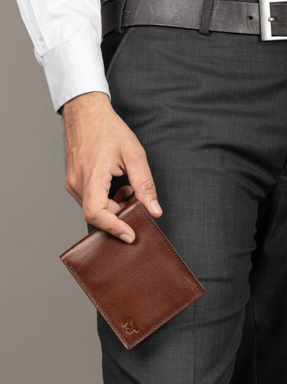Brown leather cash and card holder held in hand, embossed logo on front