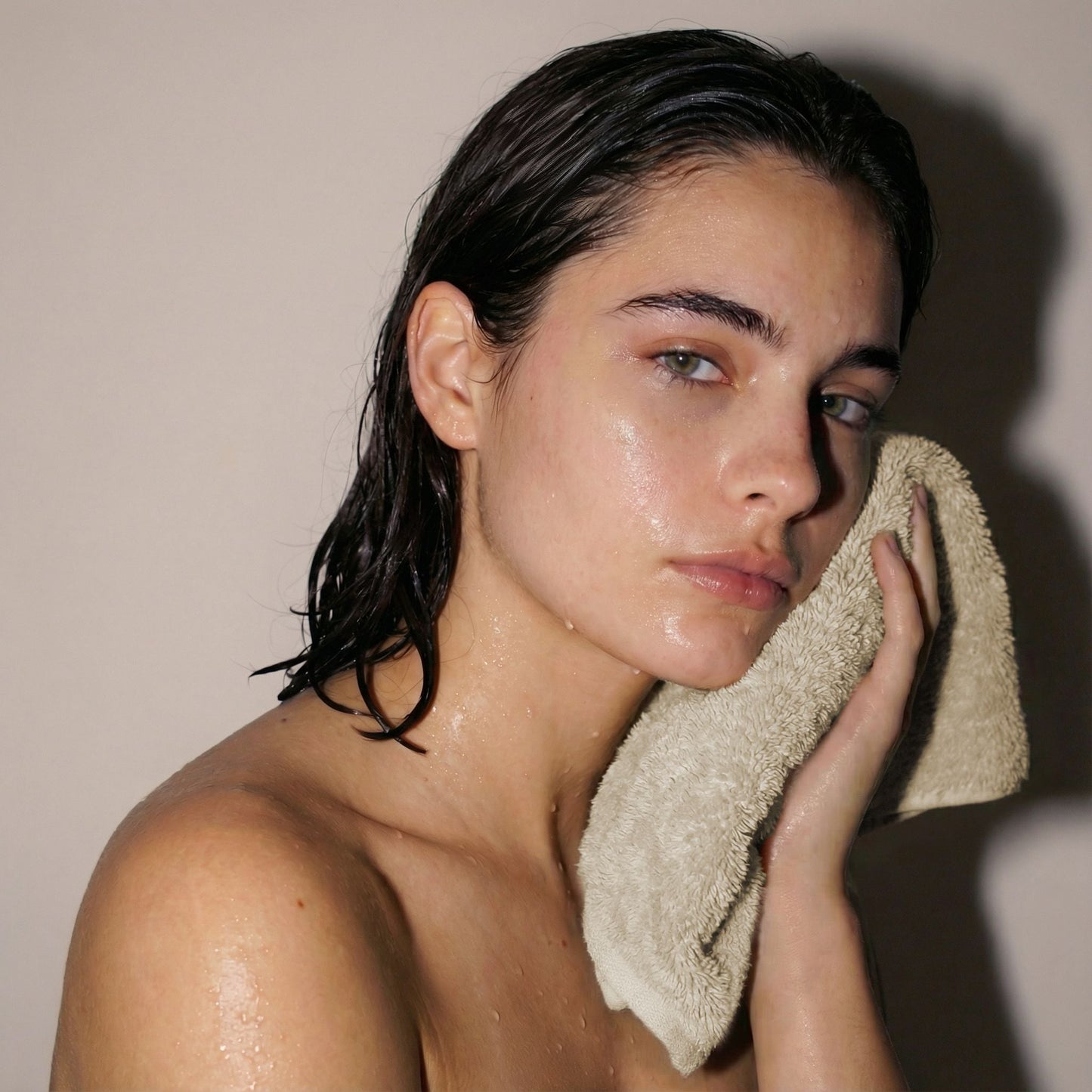 Cream cotton hand towel, plush terry texture, held close to face