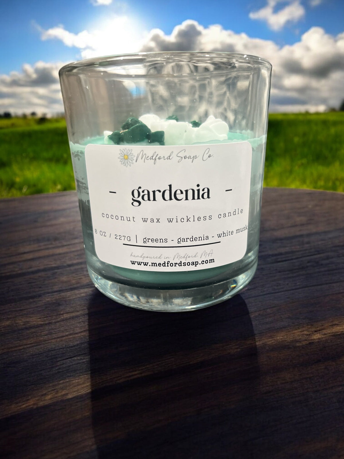 Wickless candle in clear glass jar with “gardenia” label and green-and-white wax pieces