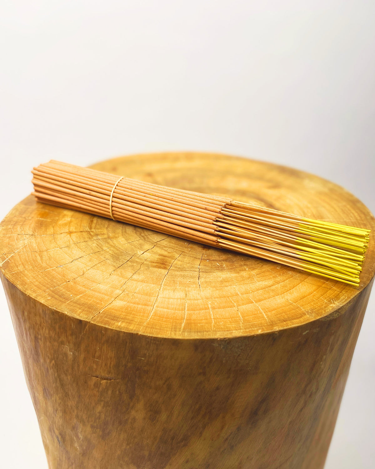 Incense sticks bundle with gold tips on a round wooden base