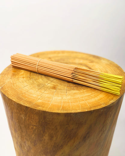 Incense sticks bundle with gold tips on a round wooden base