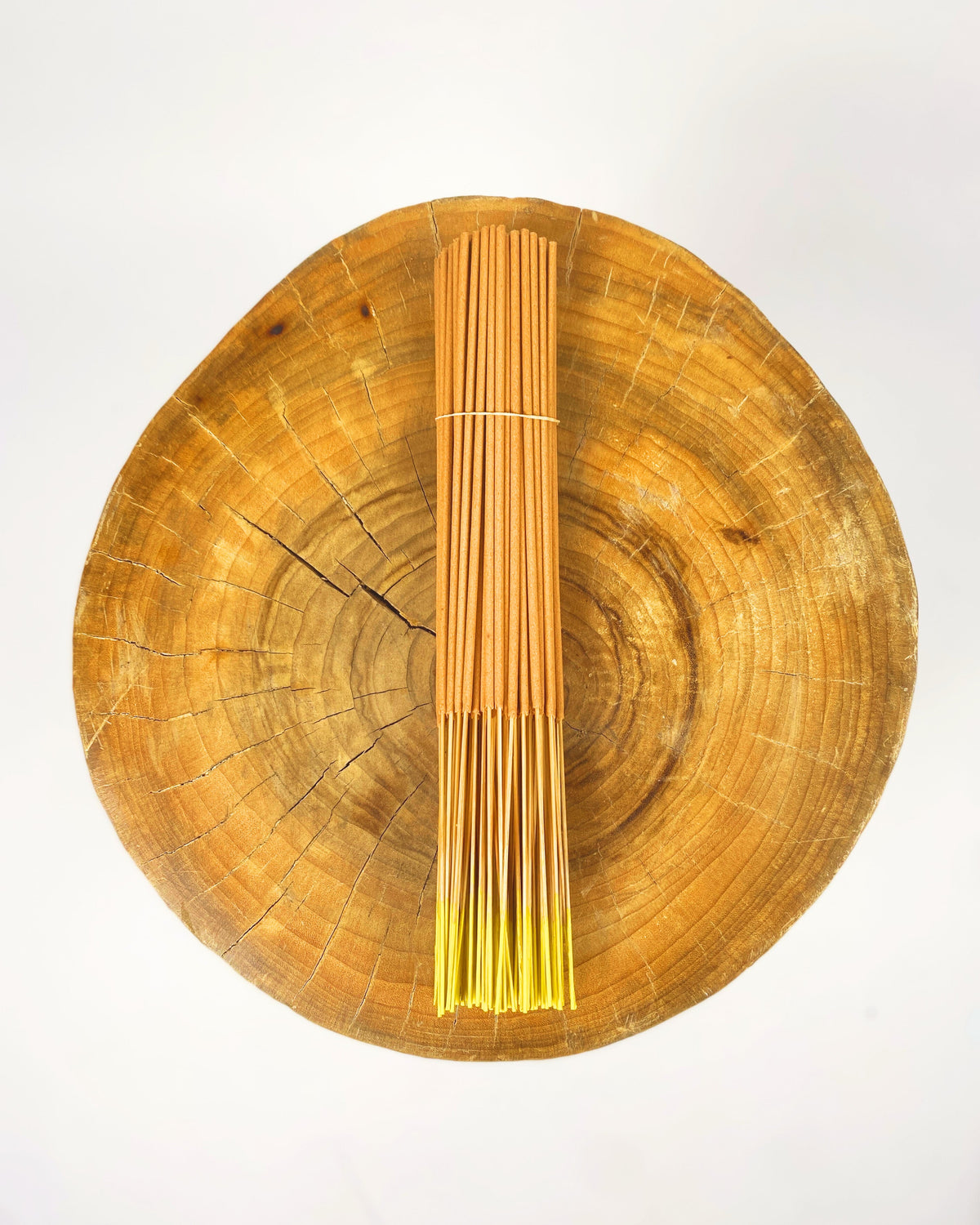 Incense sticks tied bundle standing upright on circular wooden board