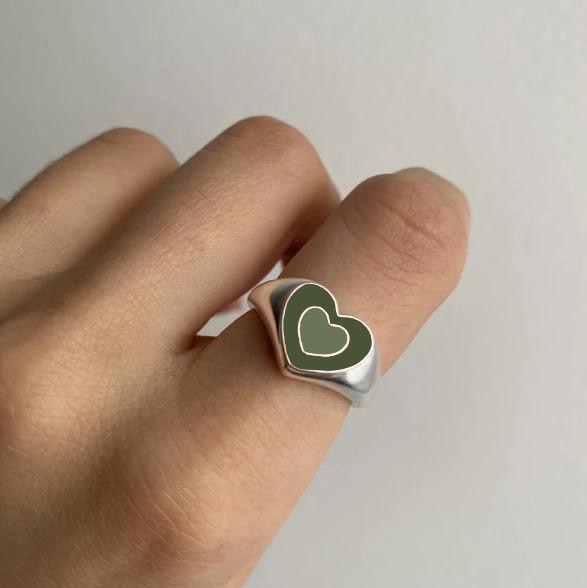 Heart-shaped ring with green enamel heart and gold-tone frame on finger