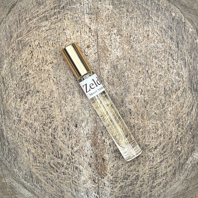 Zelda Sweet Anthem fragrance spray bottle with gold cap, shown at an angle