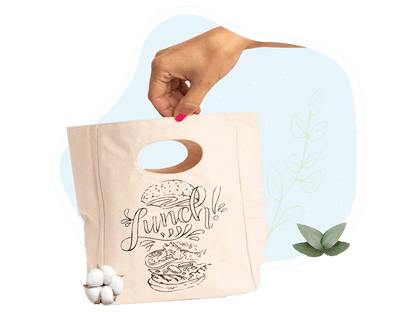 Canvas lunch bag in hand with “Lunch!” graphic and oval cutout handle