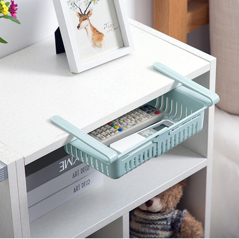 White plastic kitchen shelf organizer bin with blue handles and vented sides on a shelf