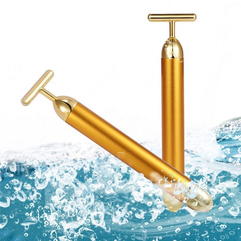 Gold T-shaped facial roller massager with waterproof tip, shown with water splash