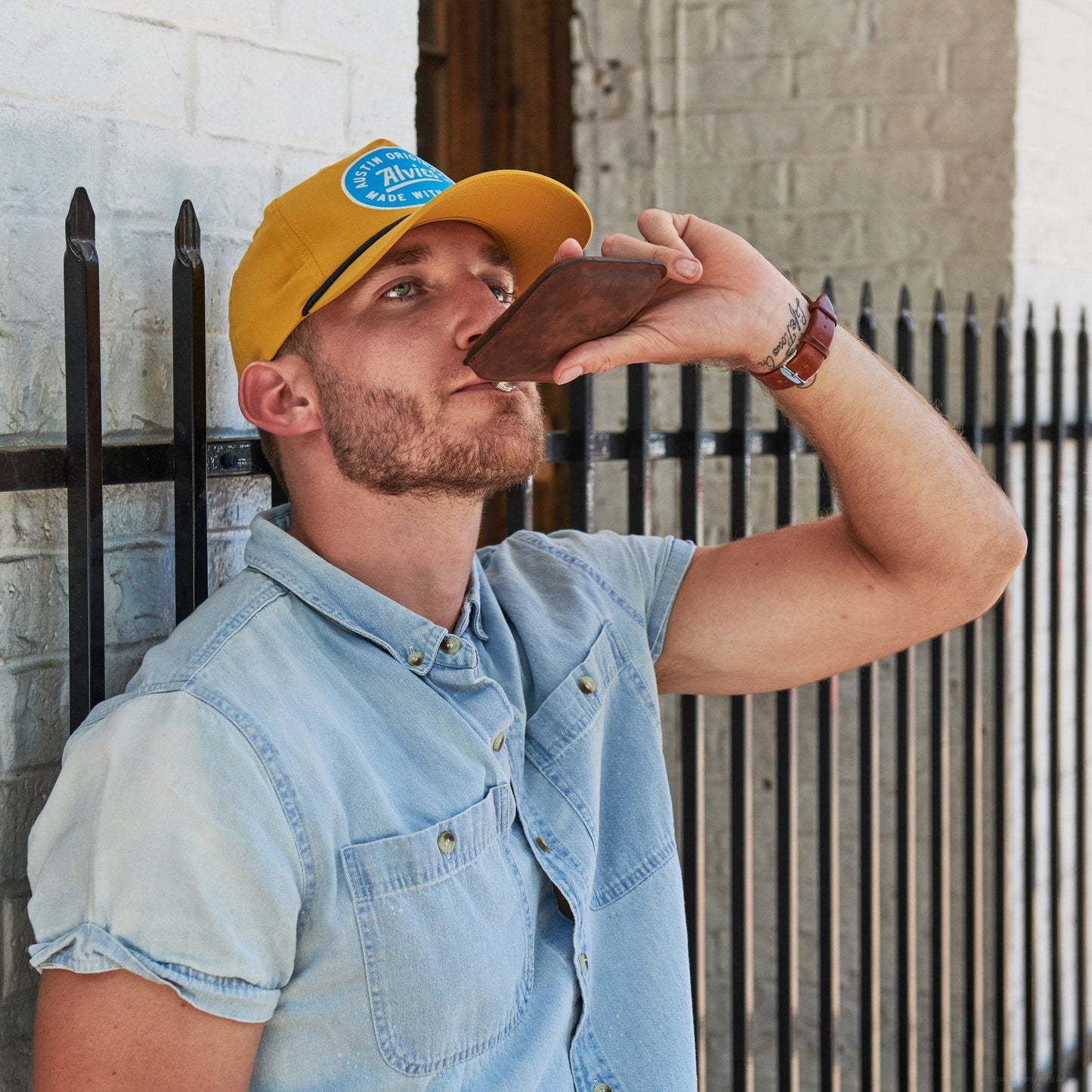 Yellow snapback hat on a person with a blue oval logo patch on the front.
