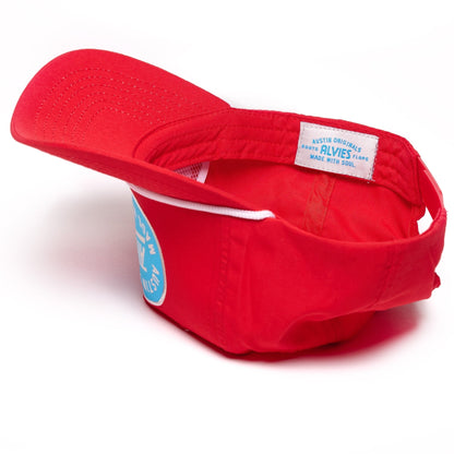 Red snapback hat, side view showing woven logo label on the cap band.