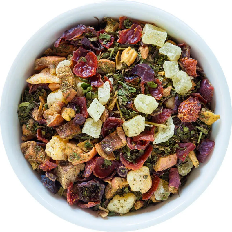 Bowl of loose herbal tea blend with dried fruit and herb pieces, multicolored.