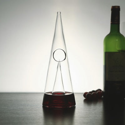 Transparent wine decanter with circular opening on top, beside a green wine bottle
